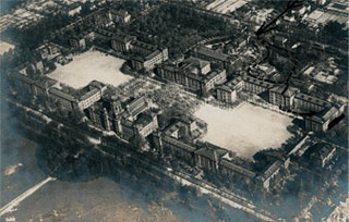 Bild: Das Gelände der ”Haupt-Kadetten-Anstalt“, aufgenommen aus einem Zeppelin in 500 Metern Höhe um 1910. Den Großteil der Anlage nahmen die vier Kasernengebäude ein, die sich symmetrisch rechts und links des Direktionsgebäudes anordneten und dadurch zwei große Innenhöfe bildeten.
