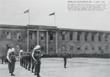 Bild: Feierliche Besatzungszeremonie am Nachmittag des 4. Juli 1945: Auf dem Dach des "halb erhaltenen" Ökonomiegebäudes die amerikanische und die sowjetische Flagge; im Vordergrund die amerikanische Militärkapelle der 2.Panzerdivision.